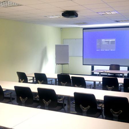 Ein moderner Seminarraum mit Computern und Beamer ist für eine digitale Weiterbildung oder Präsentation ausgestattet
