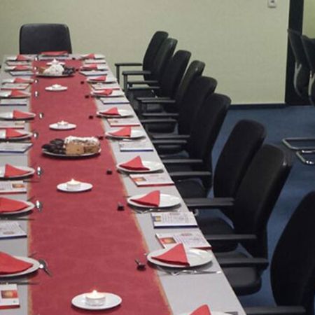 Ein großer Schulungsraum ist mit rot gedeckten Tischen für ein Seminar vorbereitet